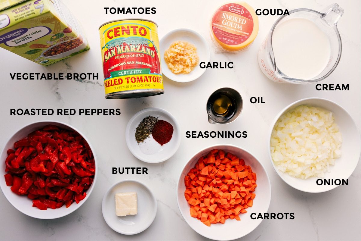 All the ingredients int his recipe prepped out for straightforward assembly including the broth, red peppers, tomatoes, seasonings, butter, oil, garlic, gouda, cream, onion, and carrots.
