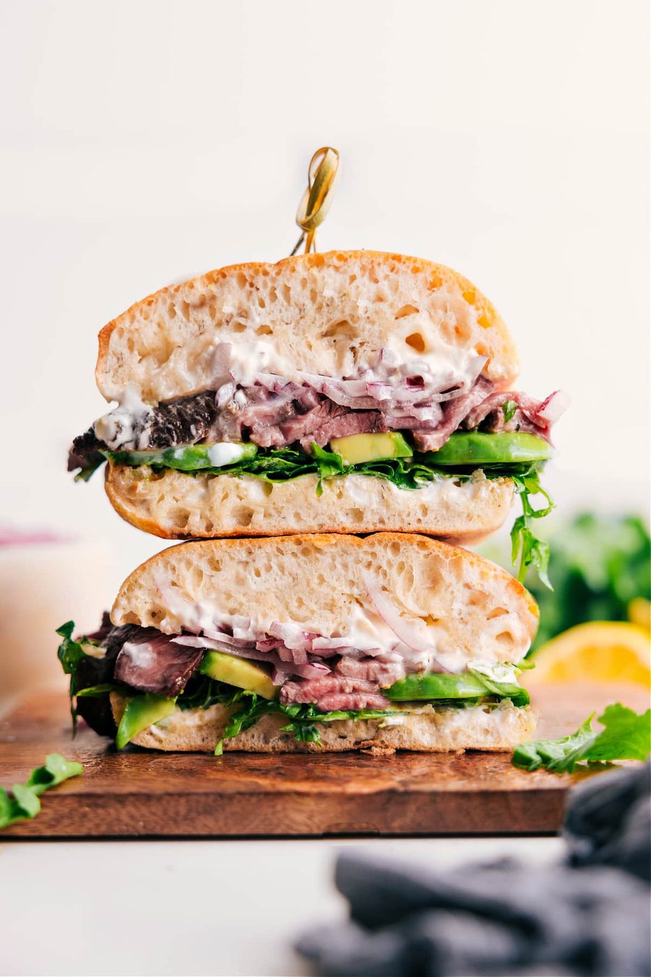 Steak sandwich recipes with sliced steak, avocado, arugula, pickled onions, and lemon aioli.