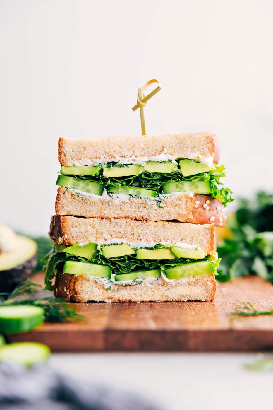 Avocado sandwich with cucumber and creamy herb spread on hearty bread.