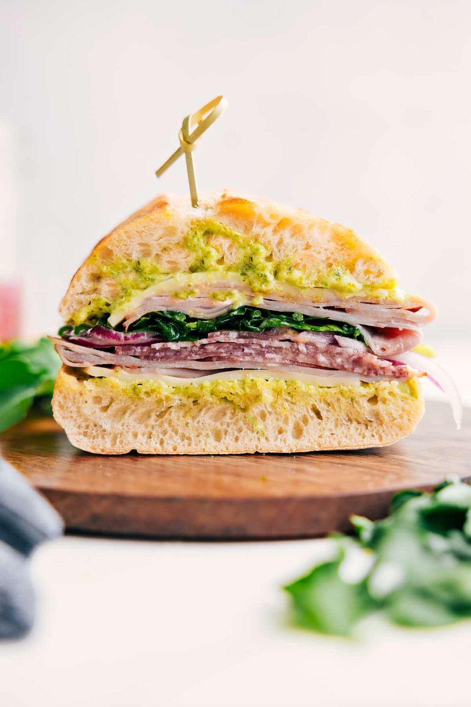 Ciabatta sandwich stacked with deli meats, provolone, pickled onions, and dressed greens.