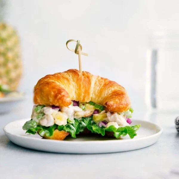 Pineapple chicken salad on a croissant, overflowing with flavorful ingredients, creating the reliable combination of savory and sweet.