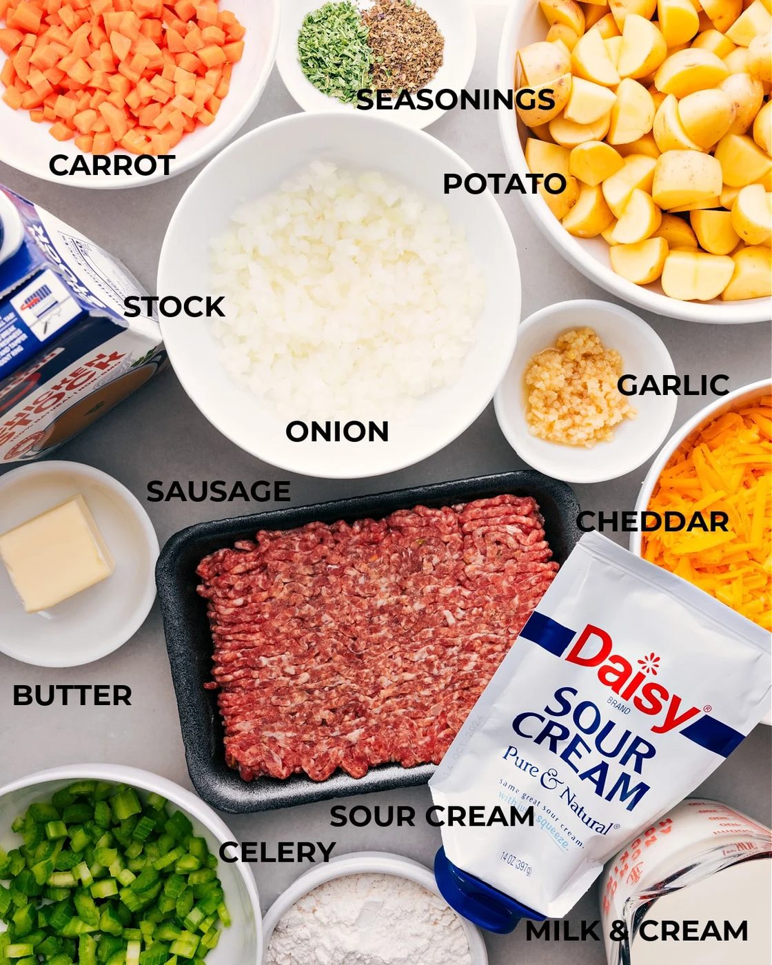 All the ingredients for this recipe are prepped, including potatoes, seasonings, veggies, meat, stock, butter, and sour cream, making assembly straightforward.