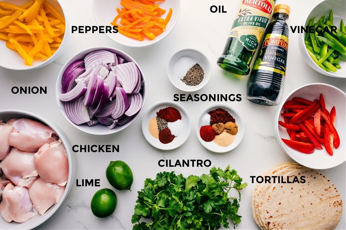 All the ingredients for this recipe prepped for straightforward assembly, including peppers, onions, seasonings, balsamic vinegar, olive oil, and tortillas.ilantro, chicken, and limes.