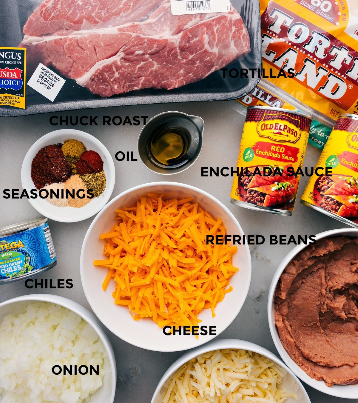 All the ingredients for this recipe are prepped for straightforward assembly, including the meat, tortillas, sauce, beans, cheese, seasonings, and chiles.