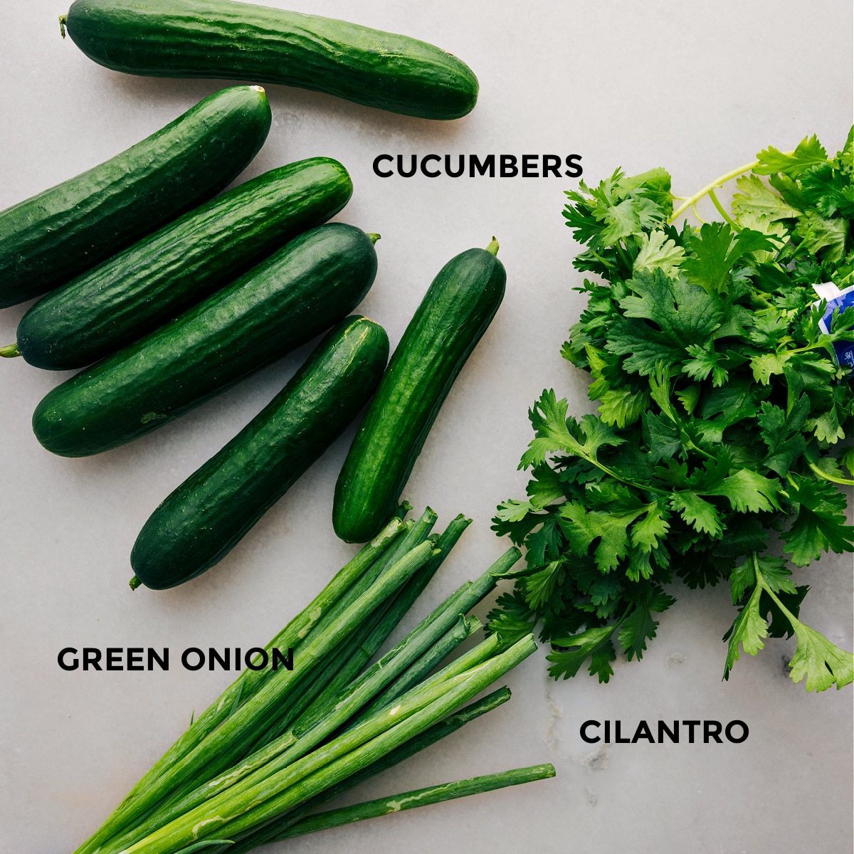 The 3 main ingredients, cucumbers, green onions, and cilantro set out to assemble this satisfying cucumber salad.
