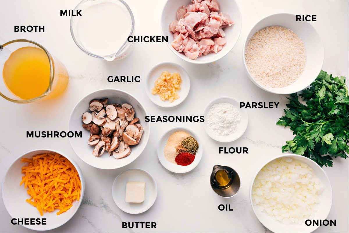 All the ingredients in this recipe prepped out for straightforward assembly including the broth, mushroom, milk, chicken, garlic, seasonings, flour, parsley, rice, oil, butter, carrots, and onion.