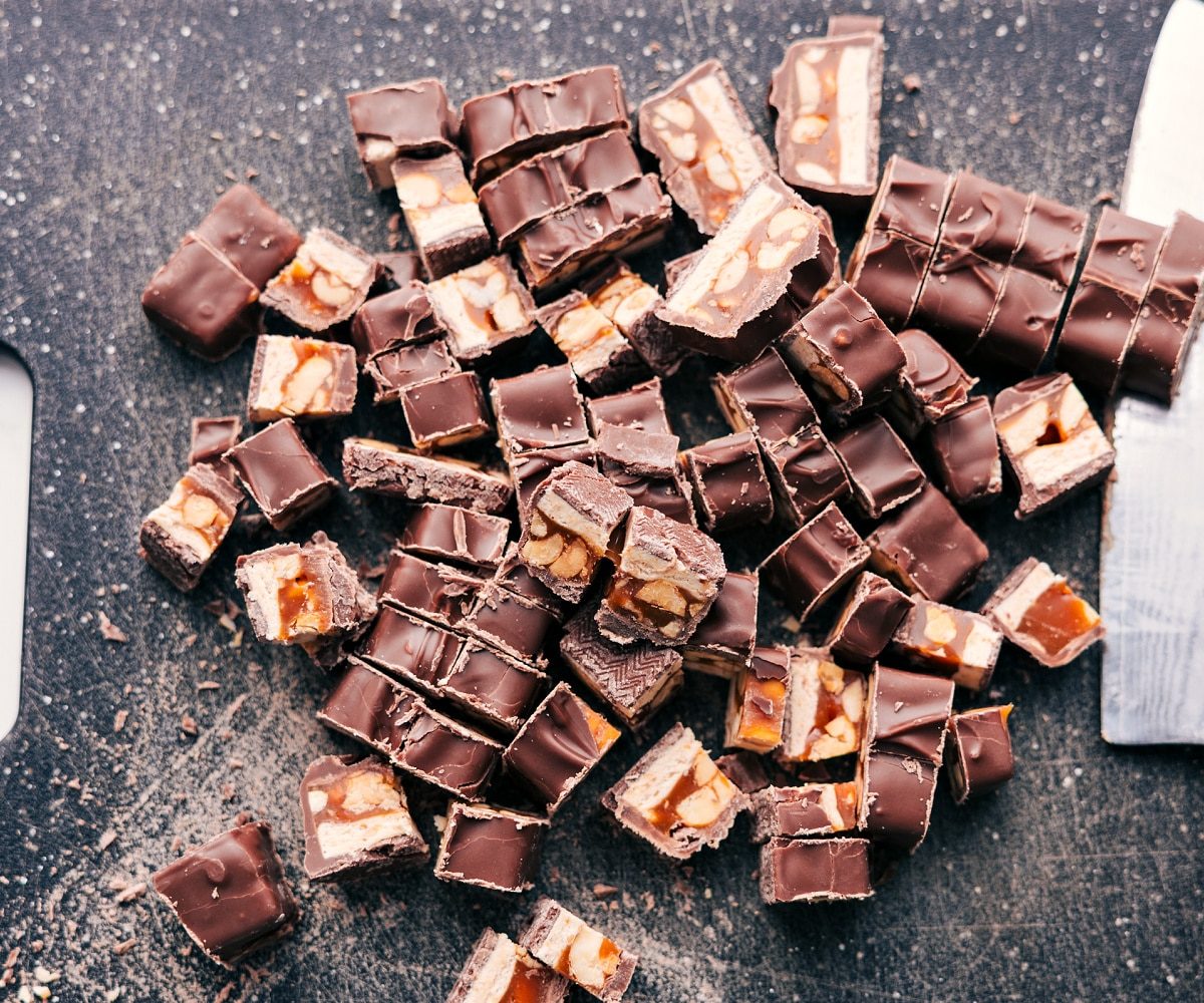 The Snickers for this Snickers salad recipe chopped up on the cutting board.