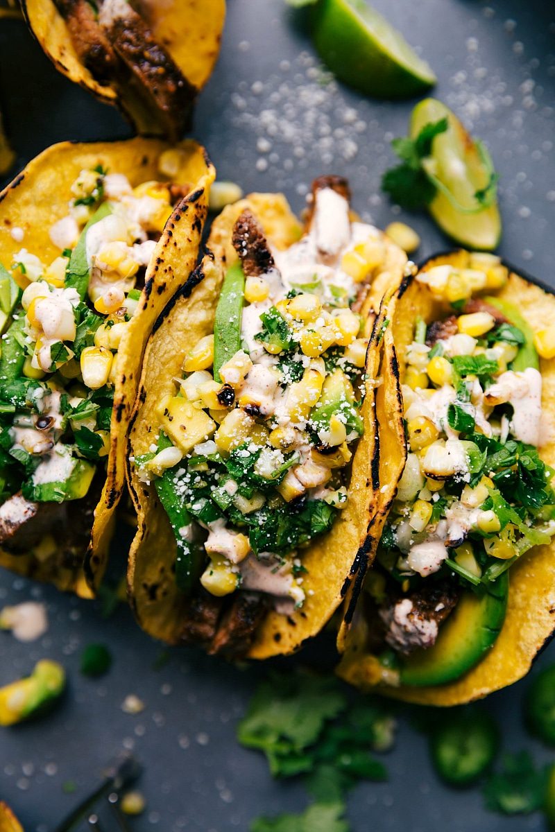 Finished steak taco recipe, with tacos side by side, stuffed with satisfying meat, corn salsa, and various toppings.