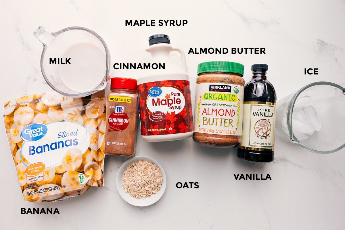 All the ingredients in this recipe prepped out for straightforward assembly including the bananas, milk, oats, cinnamon, maple syrup, almond butter, vanilla, and ice.