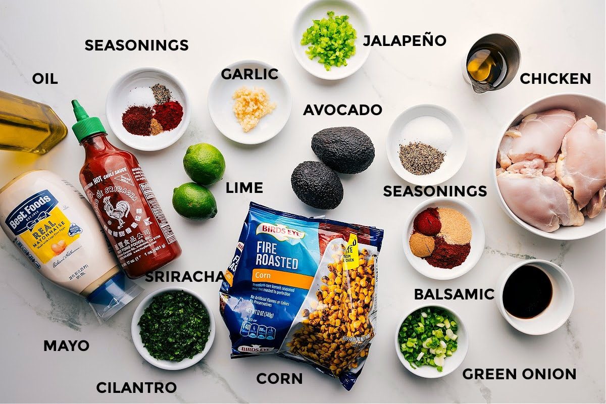 Ingredients in this recipe prepped out for straightforward assembly including the mayo, cilantro, seasonings, lime, garlic, jalapeno, balsamic, chicken, avocado, oil, green onions, and corn.