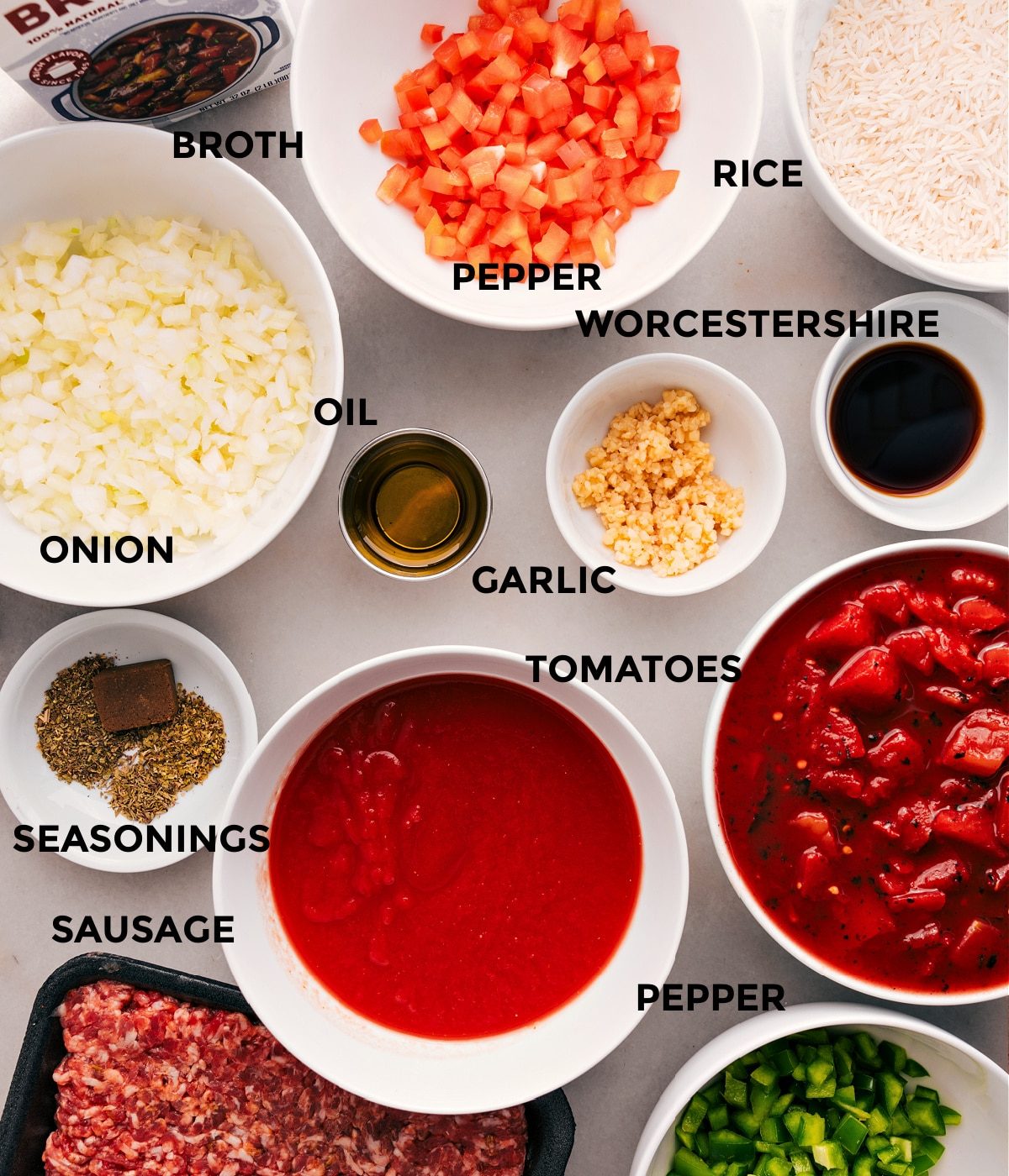 All the ingredients for this recipe are prepped and ready for straightforward assembly: peppers, onions, tomatoes, broth, meat, seasonings, garlic, Worcestershire, rice, and oil.