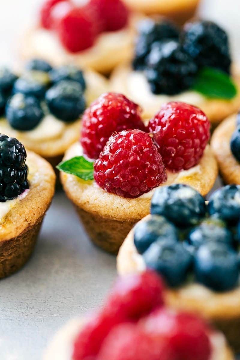 Mini fruit tarts recipe topped with raspberries, blueberries, blackberries, and fresh mint.
