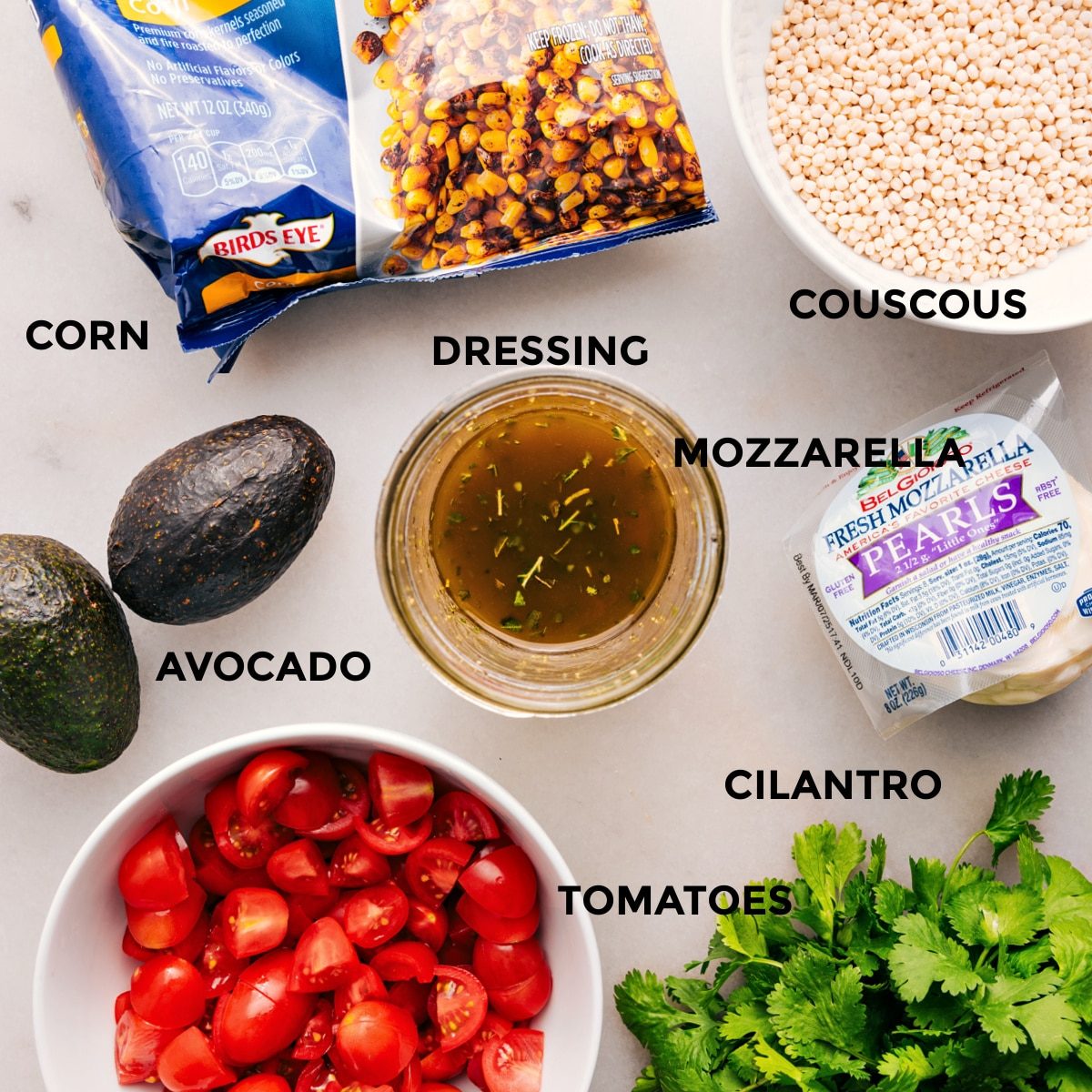All the ingredients prepped for straightforward assembly—mozzarella, cilantro, tomatoes, avocado, dressing, grain, and corn.