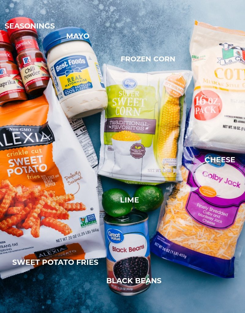 All the ingredients in this dish prepped out for straightforward assembly including seasonings, mayo, sweet potatoes, frozen corn, cotija, black beans, colby jack, and limes.
