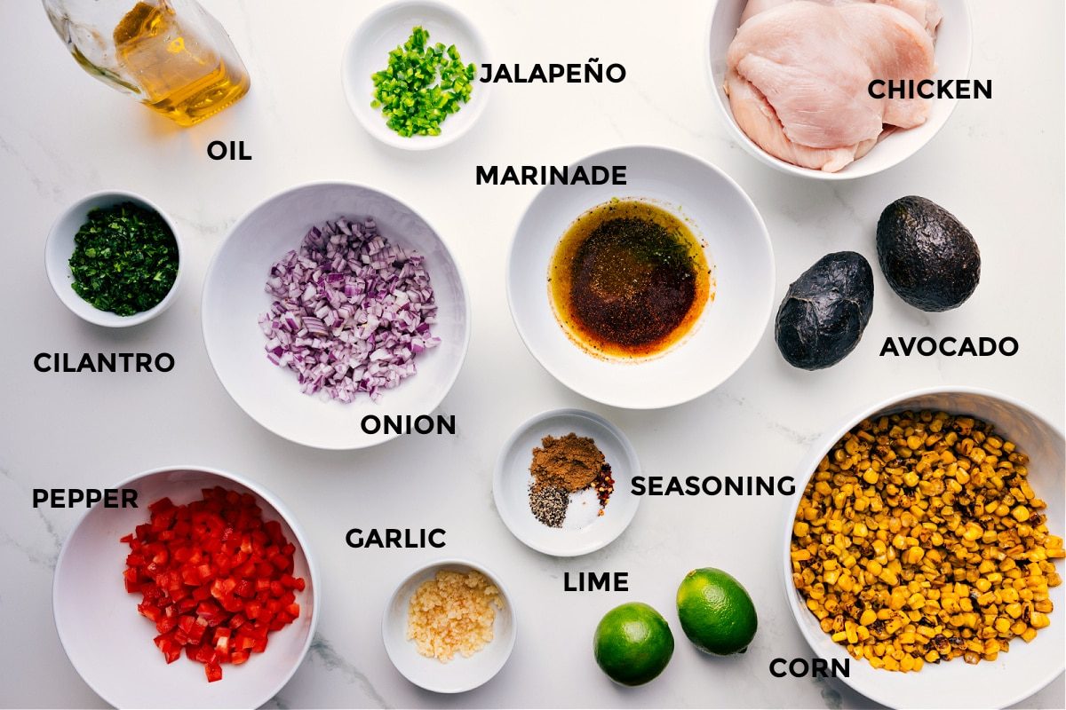 All the ingredients for this recipe are prepped and ready for straightforward assembly, including the meat, jalapeño, marinade, onion, seasonings, corn, lime, garlic, pepper, cilantro, and oil.
