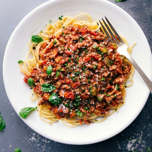 Savory and satisfying turkey bolognese on a bed of spaghetti, topped with fresh herbs.