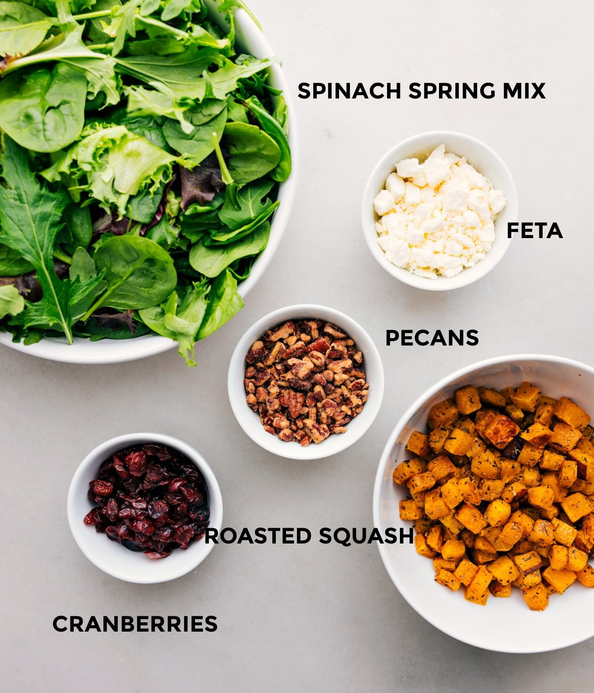 All the ingredients in this recipe, including the greens, feta, pecans, roasted squash, and cranberries, are prepped for straightforward assembly.