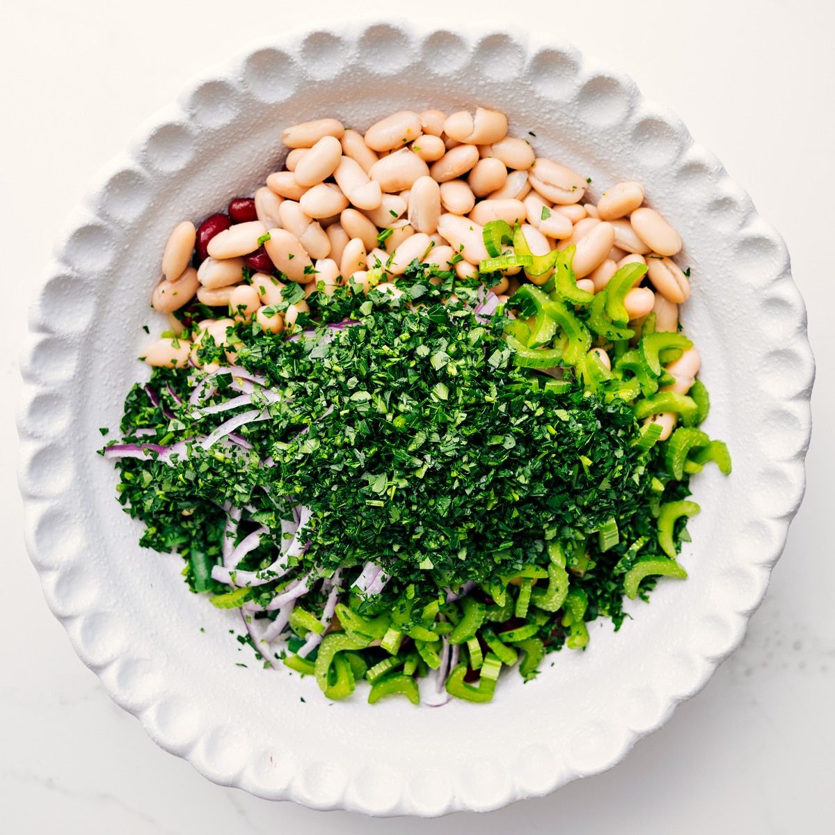 Three bean salad ingredients added to a bowl, ready to be tossed with dressing.