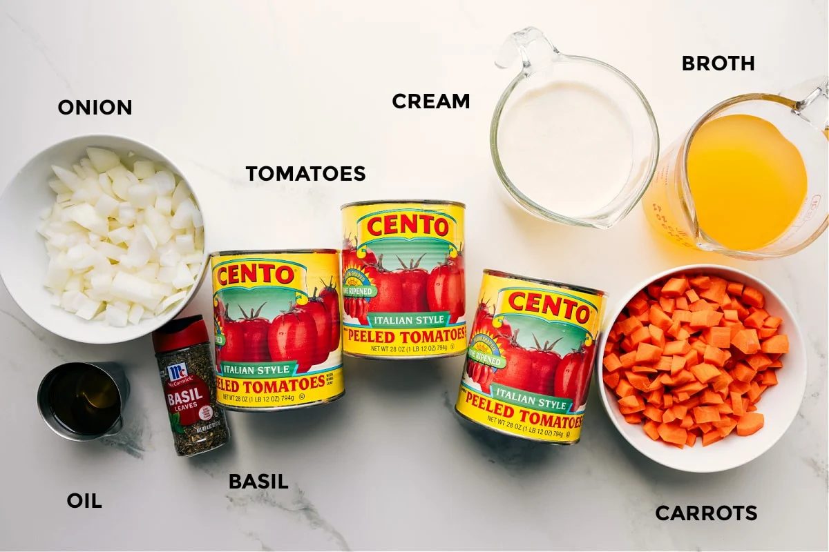 All the ingredients in this recipe prepped out for straightforward assembly including the onion, oil, basil, tomatoes, cream, broth, and carrots.