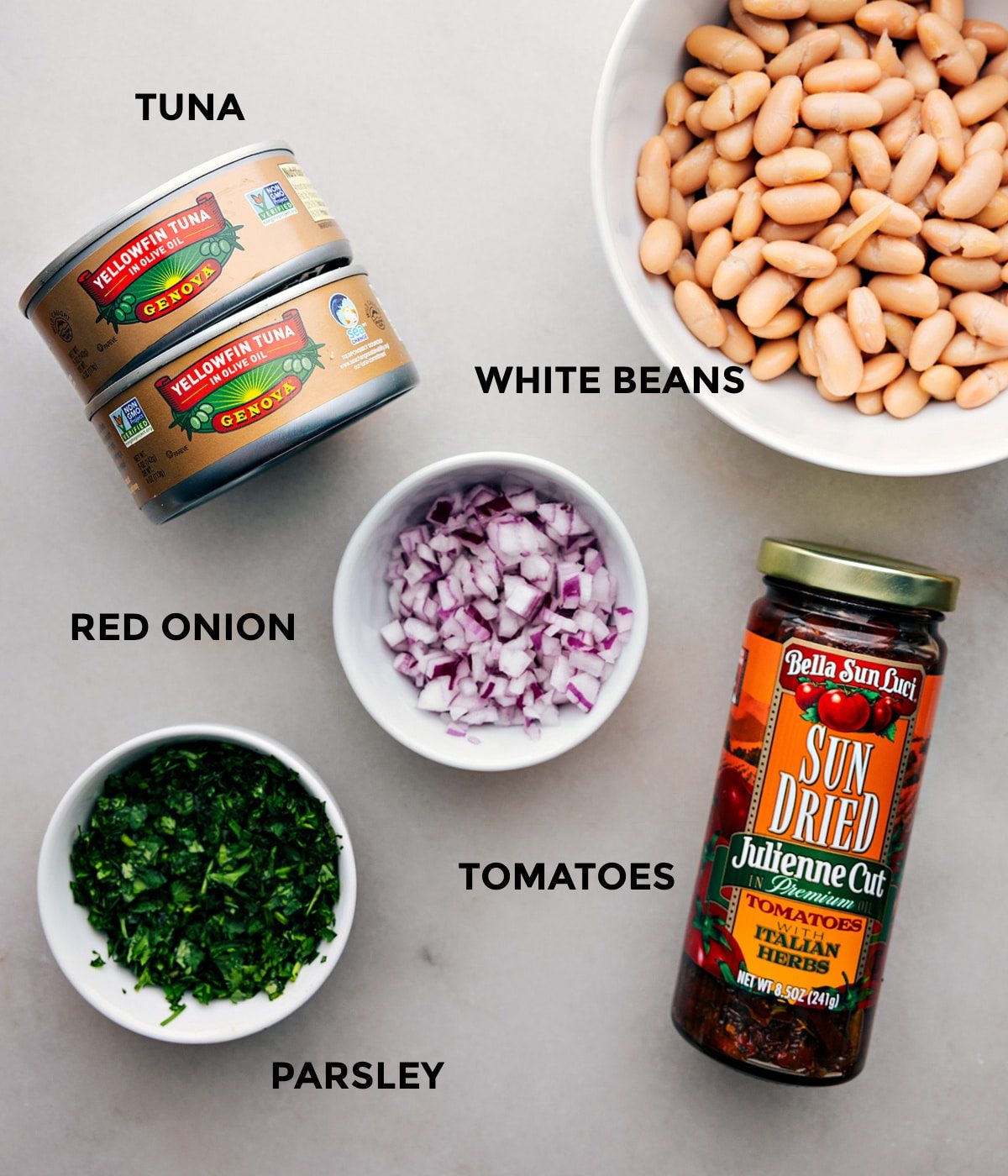 All the ingredients in this recipe including tuna, white beans, red onion, tomatoes, and parsley prepped for straightforward assembly.