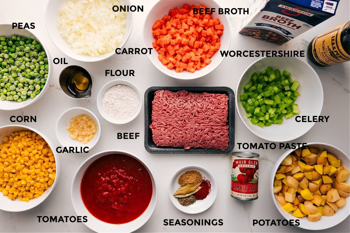 All the ingredients in this dish prepped out for straightforward assembly including the peas, corn, tomatoes, garlic, oil, onion, carrot, flour, beef, seasonings, tomato paste, potatoes, celery, Worcestershire, and beef broth.