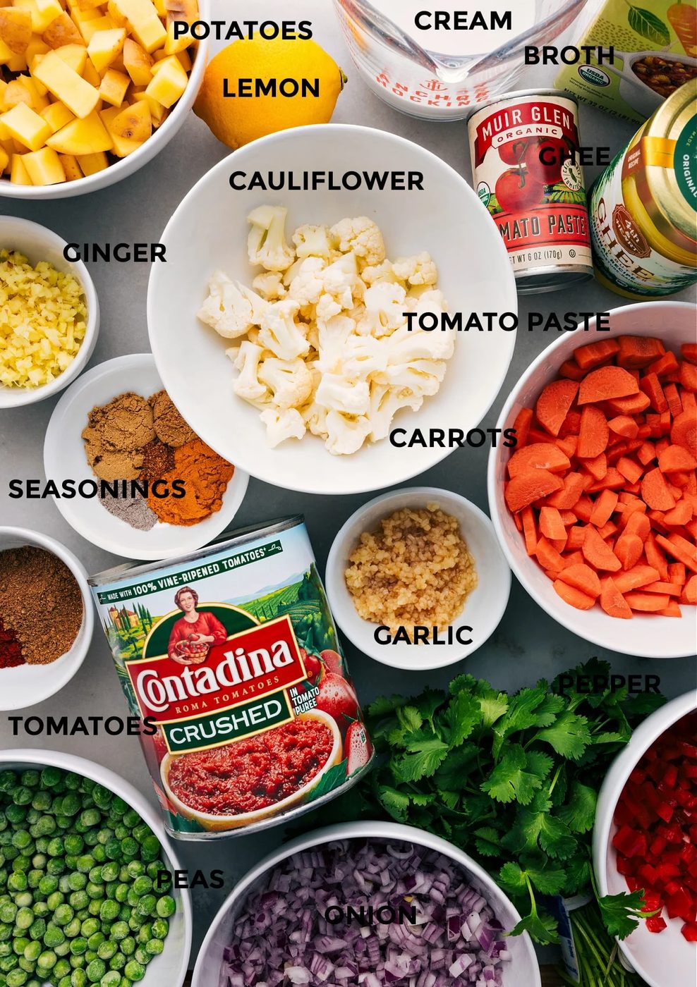 All the ingredients are prepped for straightforward assembly—veggies, seasonings, tomatoes, ghee, tomato paste, broth, cream, and lemon.