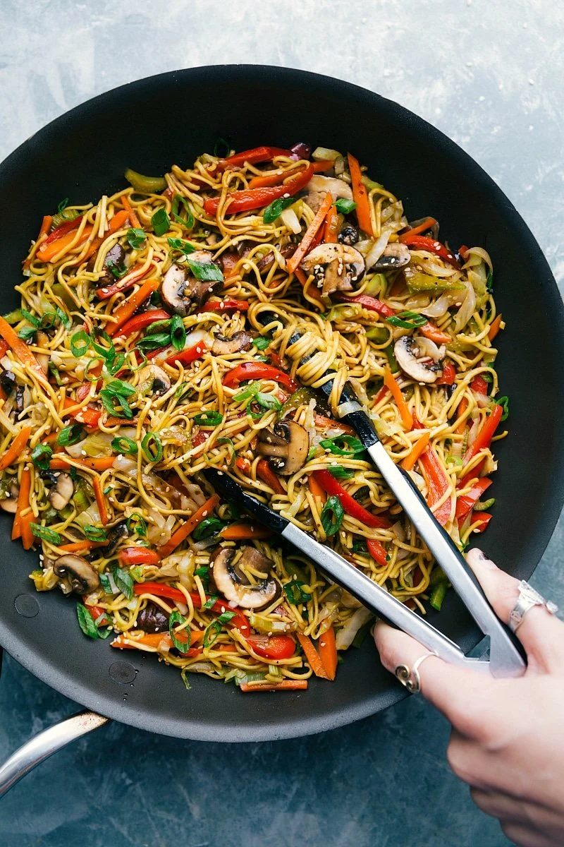 Chow Mein with tongs, ready to be served, filled with veggies and coated in a satisfying sauce.