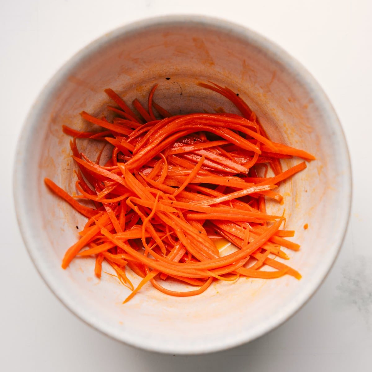 The carrots being shredded and marinated in the dressing for this veggie sandwich.