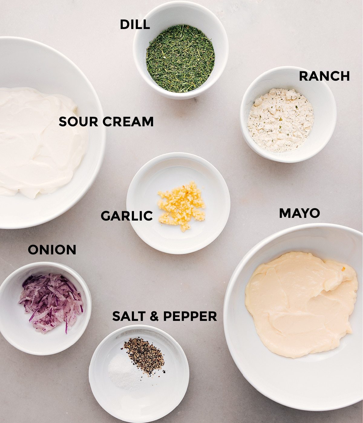 All the ingredients for this recipe—dill, ranch seasoning, sour cream, mayo, garlic, onion, salt, and pepper—are prepped and ready for straightforward assembly.