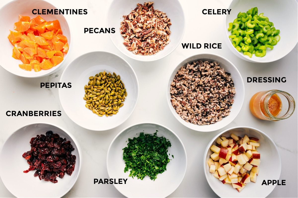 Ingredients prepped for this recipe including clementines, pecans, pepitas, dried cranberries, parsley, wild rice, apple, celery, and dressing.
