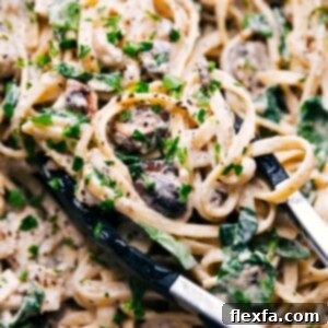 Close-up of creamy chicken pasta in a bowl, garnished with fresh parsley and grated Parmesan, showcasing its rich texture.