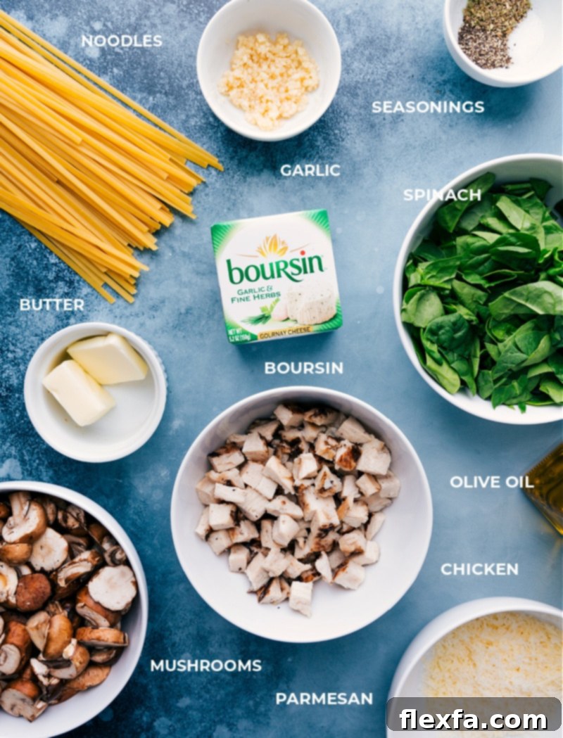 All the fresh ingredients for Creamy Chicken Pasta laid out: cooked fettuccine, shredded rotisserie chicken, fresh spinach, sliced mushrooms, minced garlic, olive oil, unsalted butter, Boursin garlic and herb cheese, Italian seasoning, salt, pepper, and grated Parmesan.