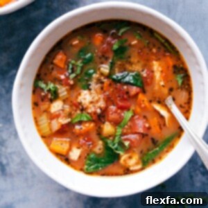 A bowl of hearty Crockpot Chicken Quinoa Soup, with chicken, quinoa, vegetables, and herbs.