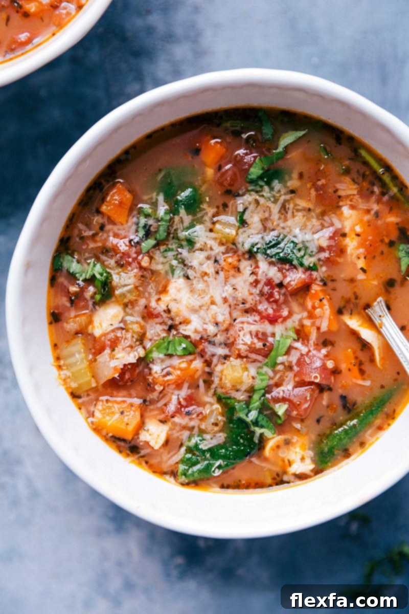 A freshly served bowl of Crockpot Chicken Quinoa Soup, richly garnished with shavings of Parmesan cheese, highlighting its comforting and appetizing appeal.