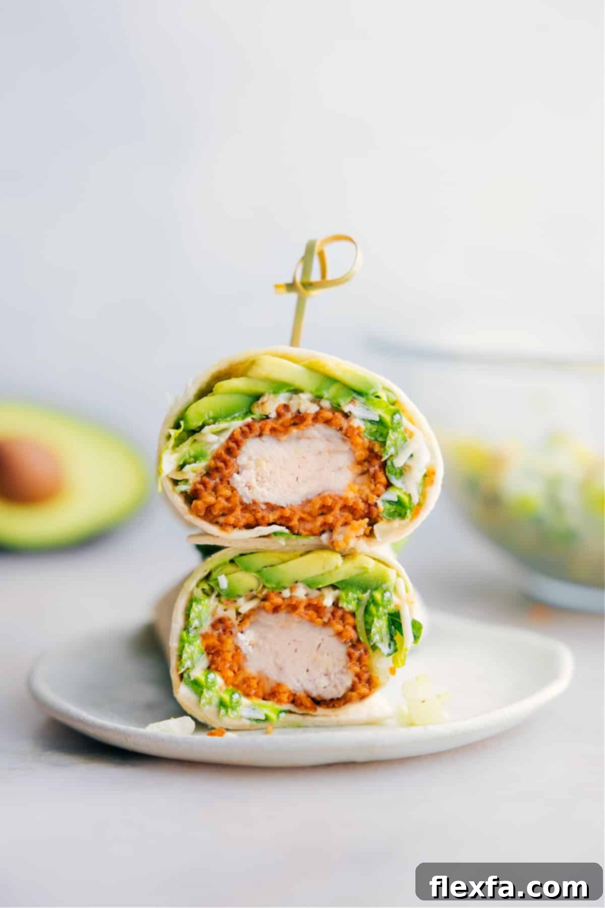 A delicious Chicken Caesar Wrap cut in half, showcasing its vibrant interior layers of crispy chicken, fresh lettuce, and creamy Caesar dressing, all encased in a soft tortilla.