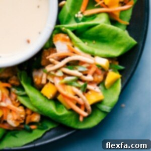 A close-up of a finished Asian Chicken Lettuce Wrap, showcasing the crispy chicken, diced mango, and crunchy noodles.