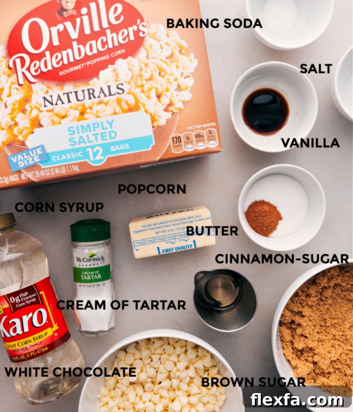All the essential ingredients for making Cinnamon Roll Popcorn are meticulously prepped and laid out: popped popcorn, baking soda, salt, cinnamon, cream of tartar, corn syrup, sugar, and white chocolate chips.