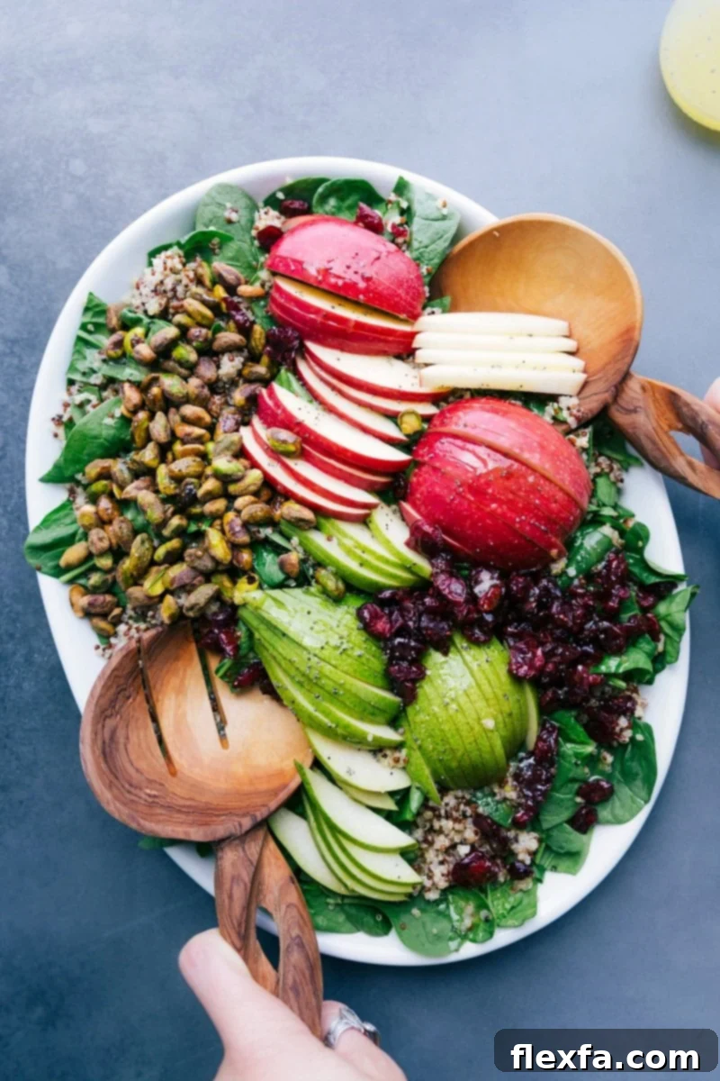 A beautifully arranged Quinoa Apple Salad on a platter, showcasing fresh greens, artfully sliced apples and pears, crunchy nuts, and sweet cranberries, ready to be served.
