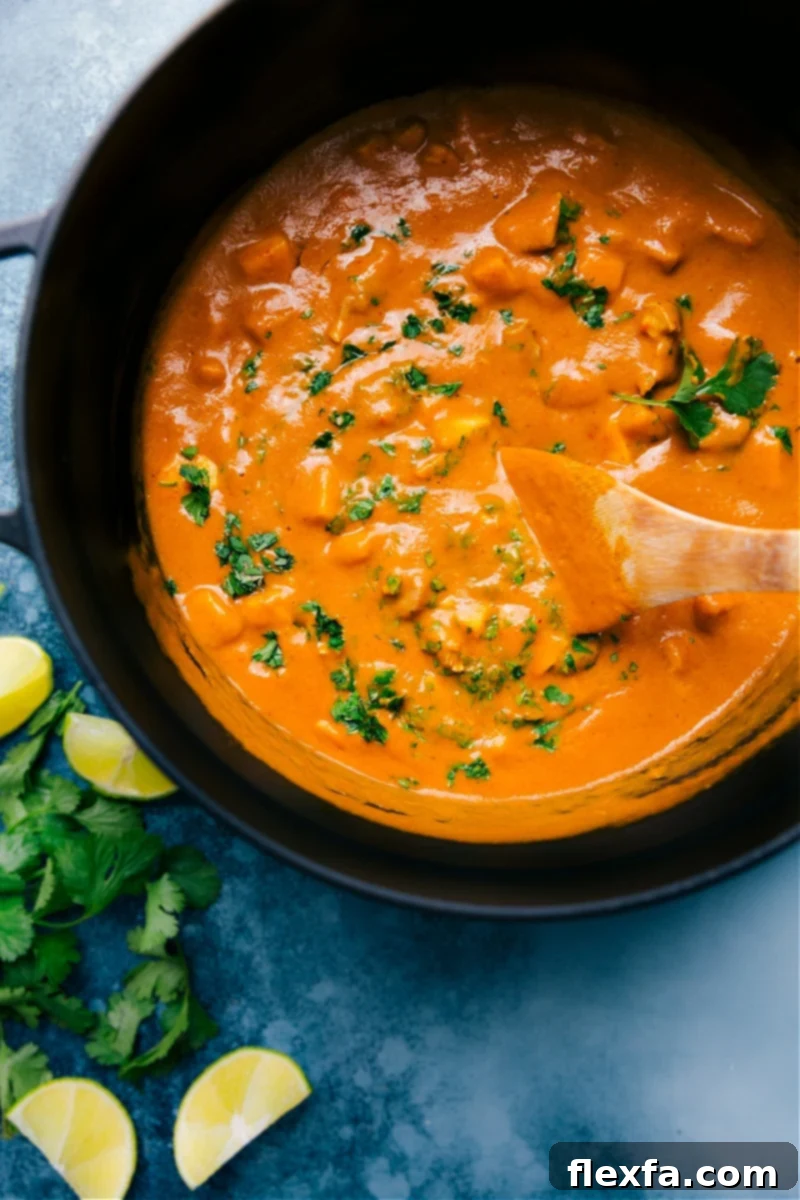 A vibrant overhead shot of Mango Chicken Curry served in a white bowl, garnished with fresh cilantro and lime wedges, alongside fluffy basmati rice.