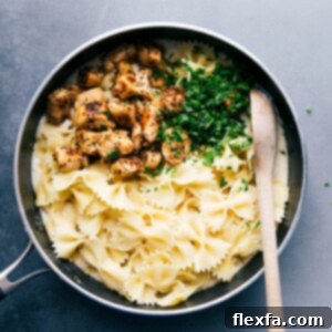 A delicious bowl of Lightened-Up Chicken Alfredo with fresh parsley garnish.