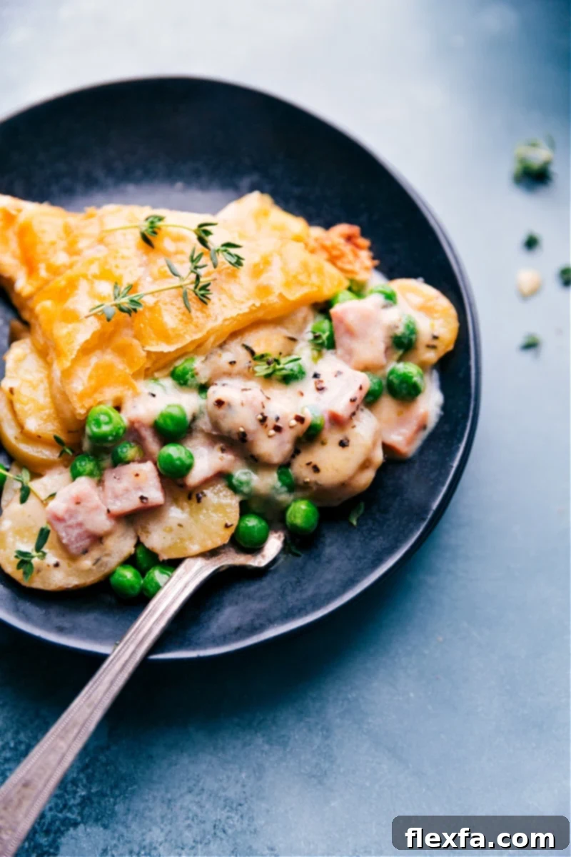 A glorious slice of Ham and Potato Pot Pie on a plate, showcasing the creamy filling and golden puff pastry.