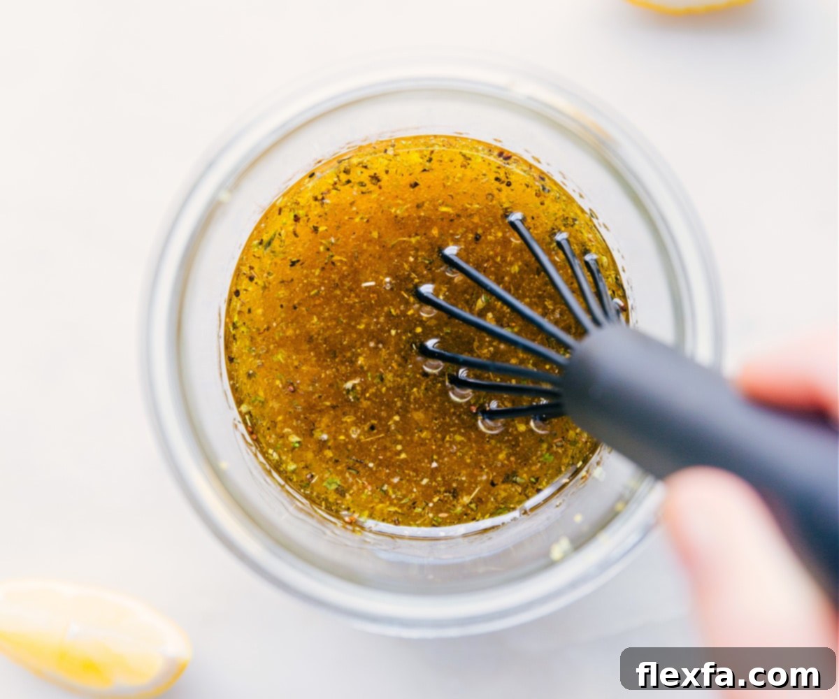Close-up of the Lemon Vinaigrette being briskly whisked in a bowl to achieve a smooth, emulsified consistency.