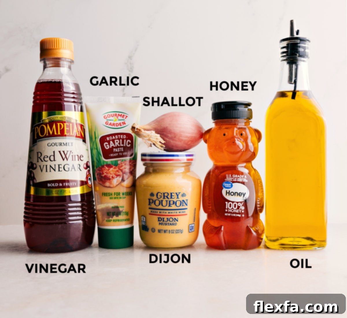 Key Ingredients for a Simple & Delicious Vinaigrette Individual ingredients neatly arranged for a simple homemade garden salad dressing: a bottle of olive oil, red wine vinegar, a jar of Dijon mustard, honey, fresh minced garlic, and finely minced shallot.