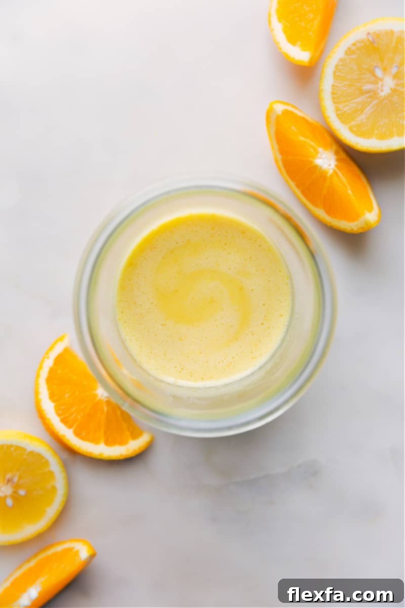 Overhead image of a beautifully golden Citrus Vinaigrette in a glass jar, garnished with citrus slices