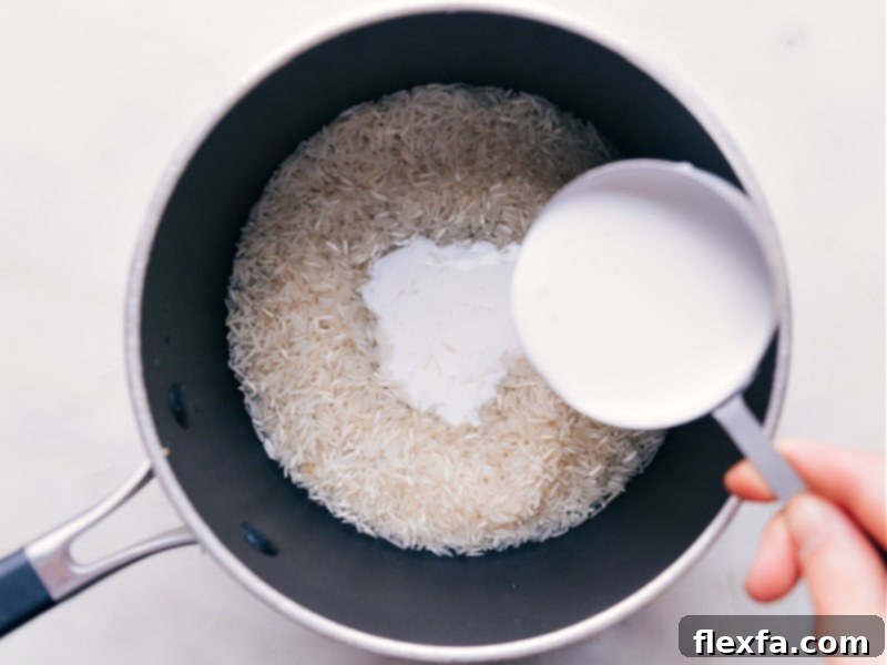 Full-fat coconut milk being poured into a pot with basmati rice and water.