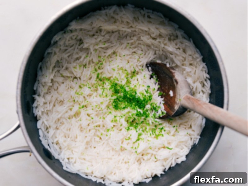 Fresh lime zest and juice being stirred into cooked coconut rice.