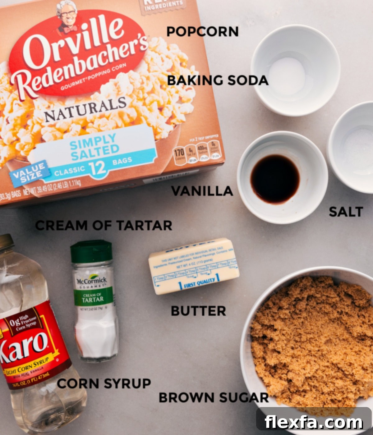 All the essential ingredients for making homemade caramel corn are neatly prepped on a counter, including plain popcorn, butter, sugar, corn syrup, salt, baking soda, and vanilla extract.
