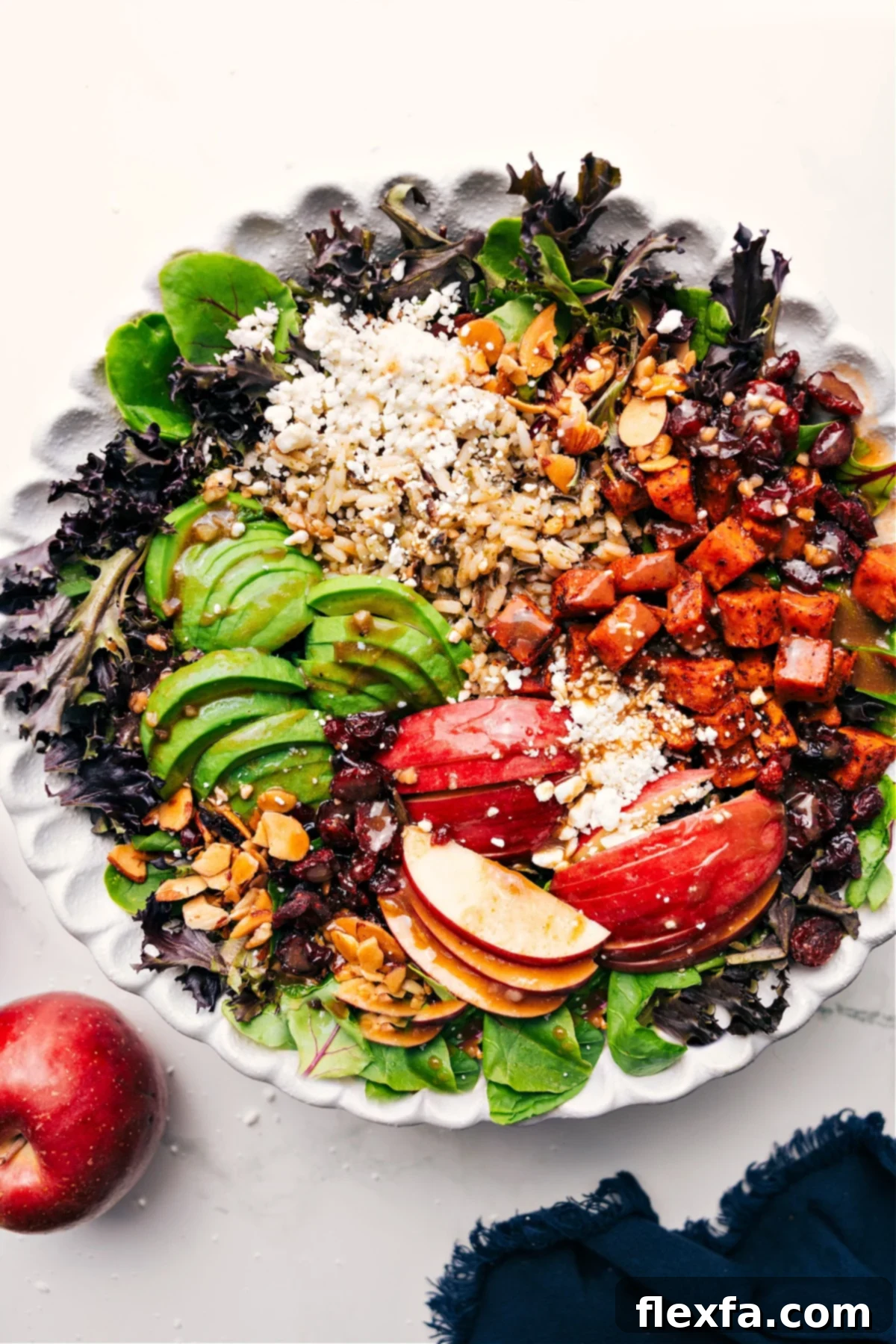 A vibrant Fall Harvest Salad in a large wooden bowl, with individual ingredients like roasted sweet potatoes, apple slices, cranberries, and greens visible, ready to be tossed with dressing.
