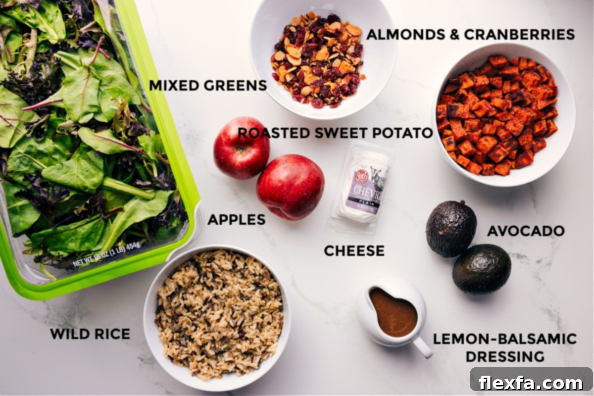 All the vibrant ingredients for the Fall Harvest Salad beautifully prepped and arranged for easy assembly, including mixed greens, cooked wild rice, sliced almonds, dried cranberries, perfectly roasted sweet potatoes, creamy avocado, and optional crumbled cheese, alongside a jar of homemade dressing.