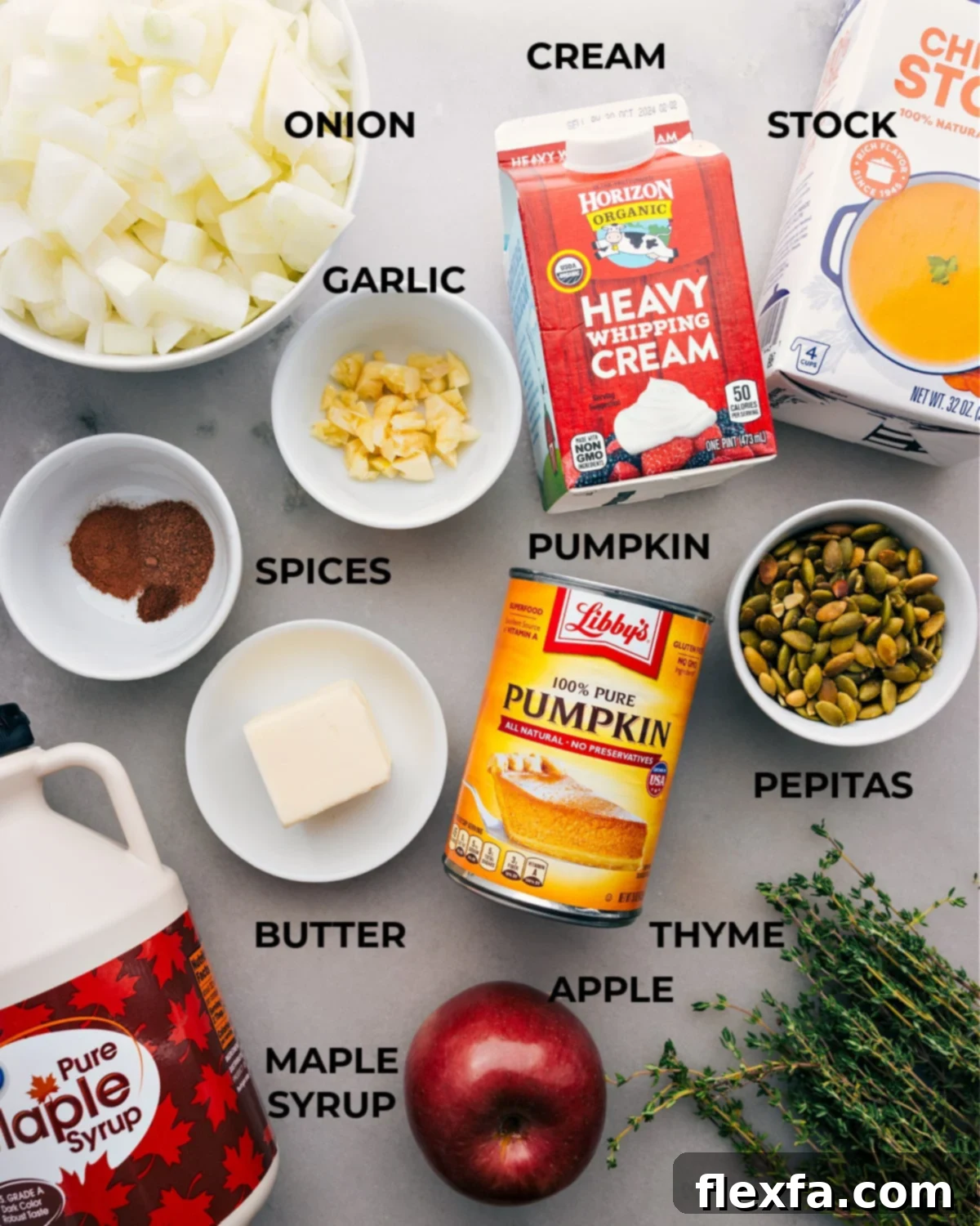 All the essential ingredients for making this delicious pumpkin soup, including onions, heavy cream, stock, aromatic spices, garlic, canned pumpkin puree, and optional pepitas for garnish.